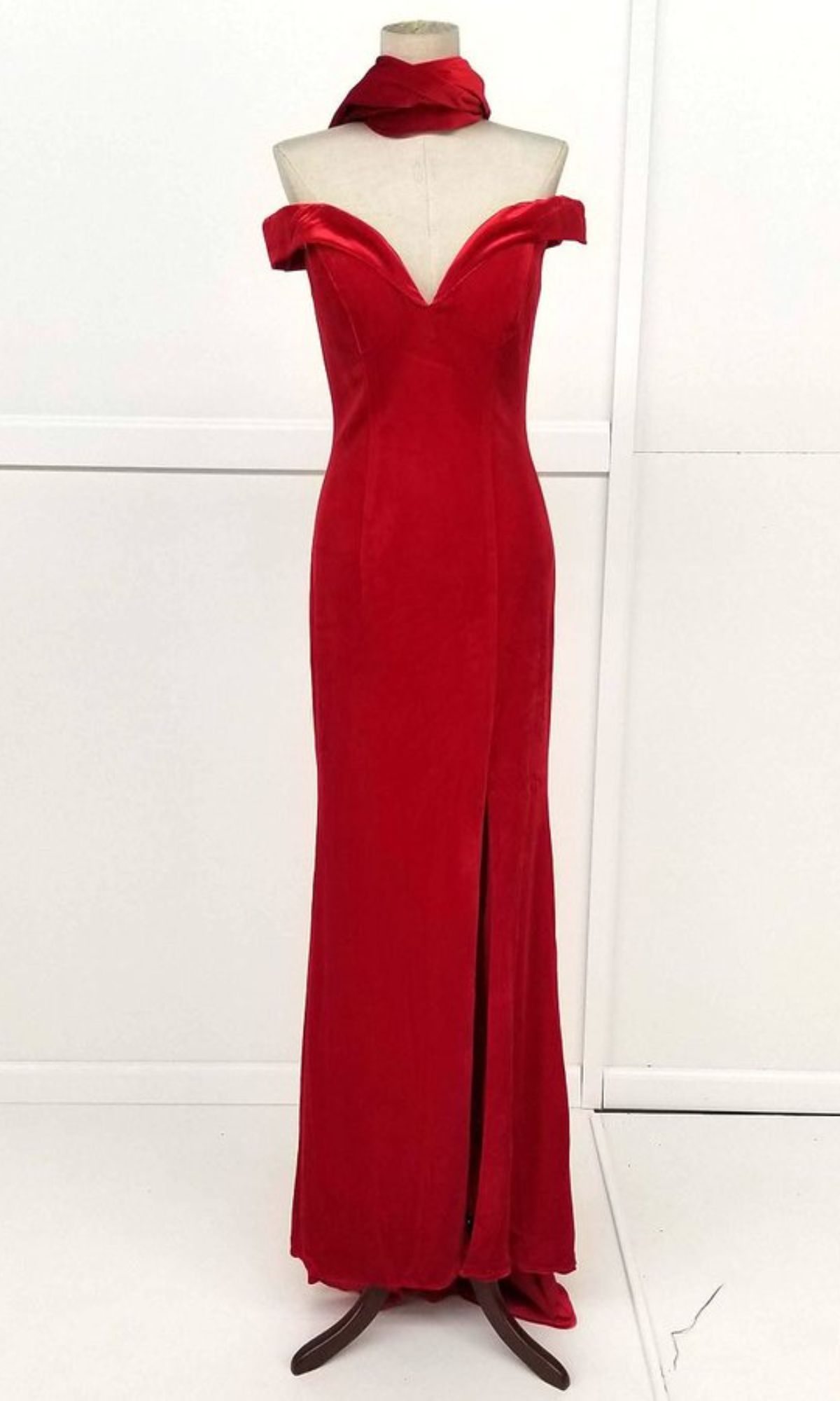 The Off-the-Shoulder Long Prom Dress: Chicas C6532, featuring a red hue, sweetheart neckline, thigh-high slit, and matching scarf, is elegantly displayed on a dress form.