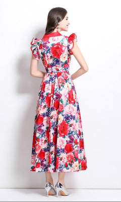 Model showing the back of a multi-color red floral maxi dress standing in front of white background.