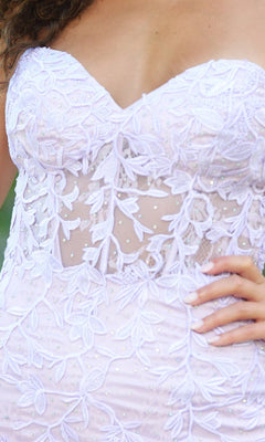 A close-up of a woman wearing the Velvi Strapless Sweetheart Short Party Dress Reva, featuring white floral lace, sheer paneling, and delicate embroidery, her hand resting on her hip.