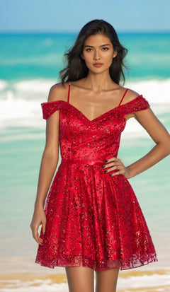 A woman stands on a beach in the Cold-Shoulder Glitter Homecoming Dress 9198, a red dress with thin straps and an elegant A-line skirt. The sea and blue sky form the backdrop.