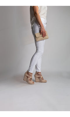 A person wearing white pants, a white short-sleeve shirt, holding a beige clutch, and sporting Rory Beige Wedge Prom Shoes: Touch Ups 4475 stands against a plain light background.