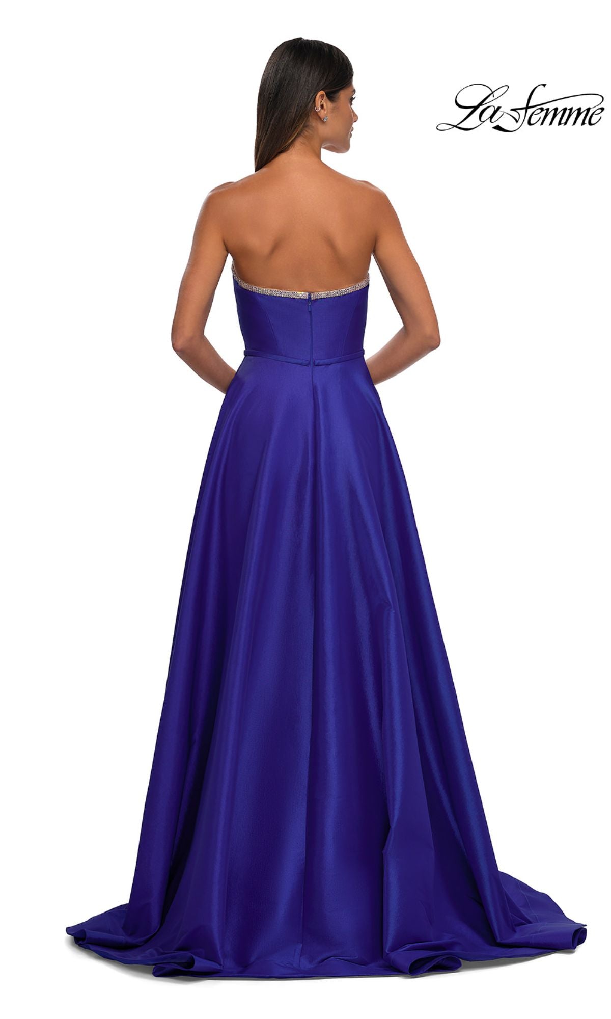 A woman stands with her back to the camera, wearing the La Femme 33063 strapless long a-line prom dress in royal blue. The fitted gown features a slight train, with the 