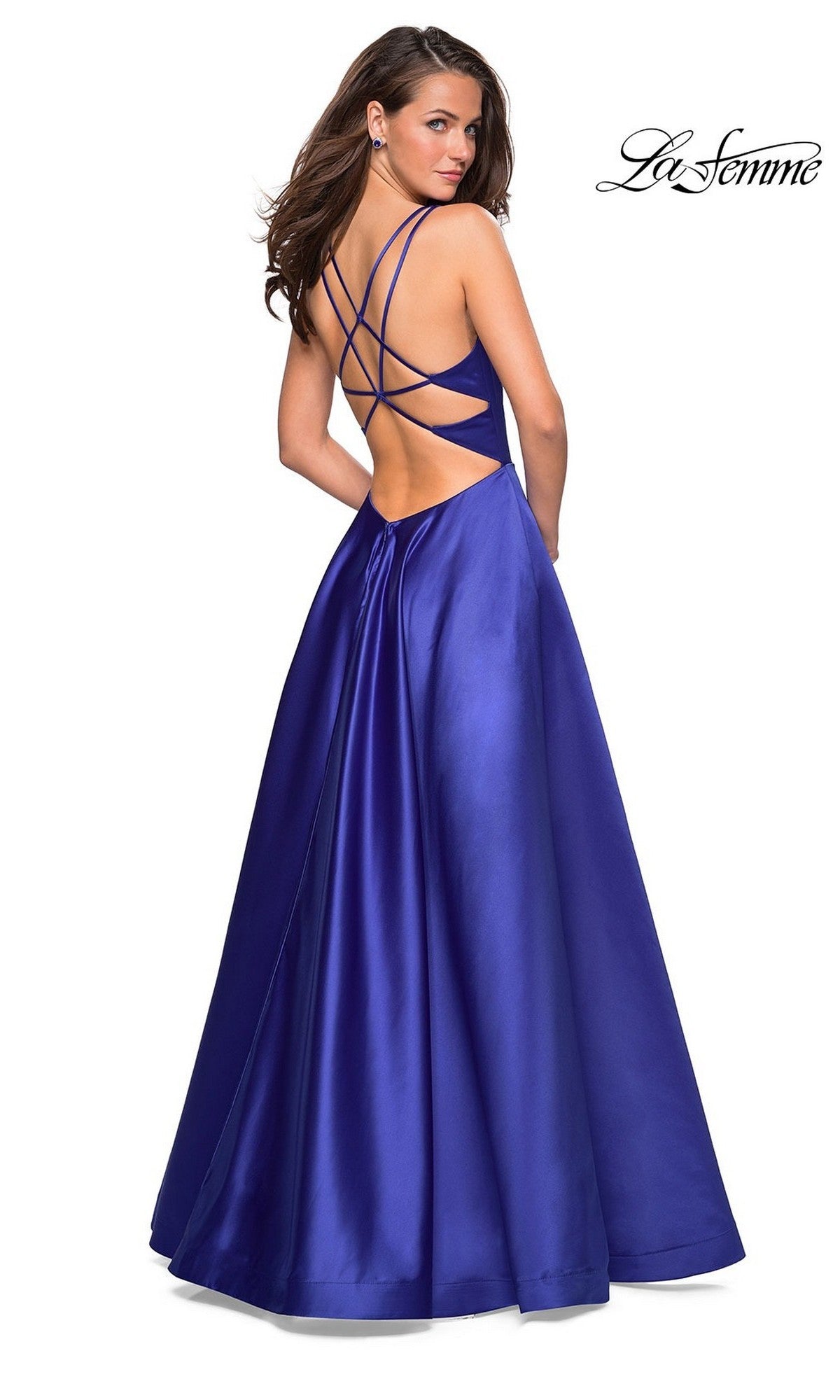 A woman poses against a white background in the La Femme Deep V-Neck Long A-Line Prom Dress 26994, a floor-length royal blue satin gown featuring a strappy open back, looking over her shoulder.
