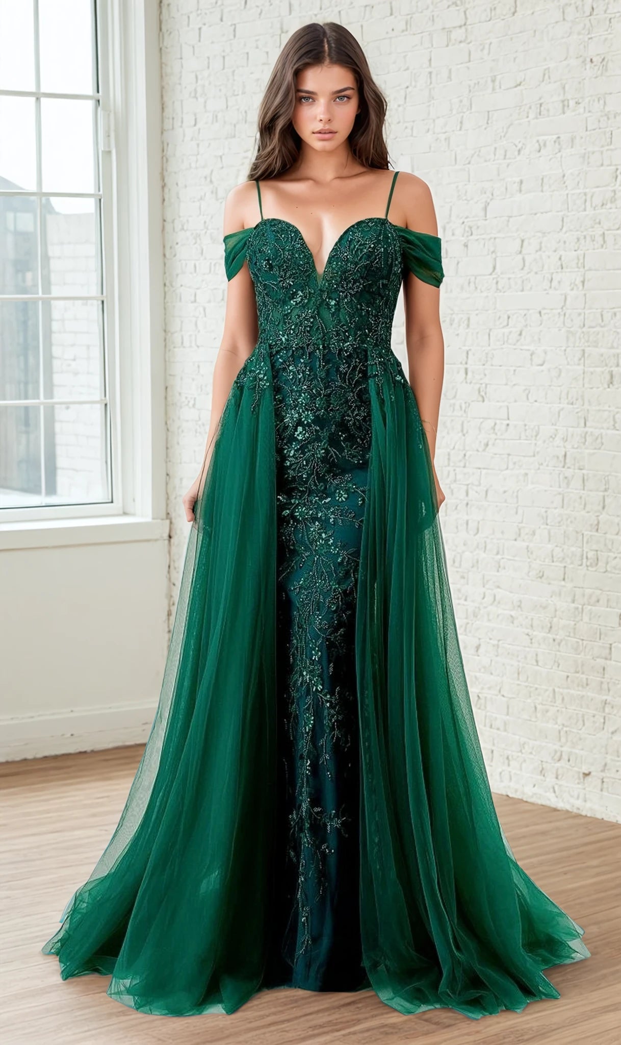 Woman wearing a green evening gown with lace detailing in a room with a window and white brick wall.