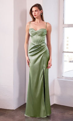 A woman stands indoors wearing the Amoris T608 Long Sweetheart Prom Dress, a light green satin gown featuring a corset-style bodice, thin straps, and a thigh-high slit.