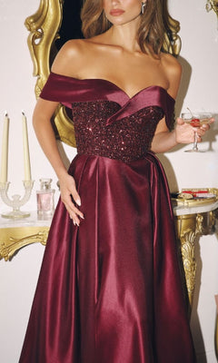 Woman in a burgundy evening gown holding a cocktail in an elegant setting.