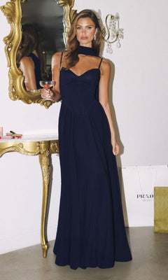 Woman in a navy blue evening gown standing in front of a mirror with gold frame.
