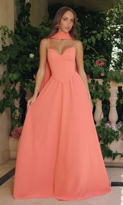 Woman wearing a coral pink gown holding the a-line skirt in an outdoor setting.