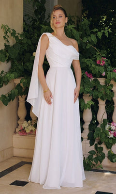 A woman in the Asymmetrical Off-White Bridal Gown: Amoris T716W, featuring a long chiffon skirt, stands on a tiled patio before greenery and a stone railing.