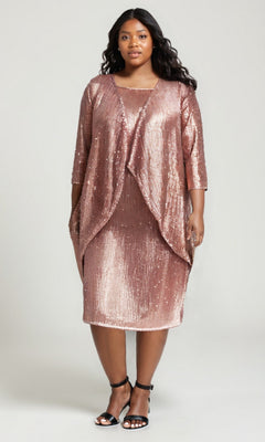 A woman models the Amoris T9001 Plus-Size Two-Piece Party Dress in rose gold, featuring a sequin-embellished knee-length dress and matching draped jacket, styled with black ankle-strap heels against a plain background.