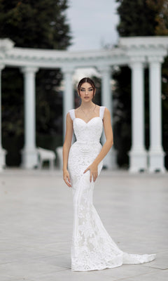 A woman wearing the Off-Shoulder White Bridal Gown: Tina Holly TW103 stands outdoors before white columns and lush greenery.