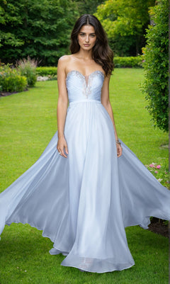 A woman wears the La Femme Designer Pleated Chiffon Prom Dress 20027 with a strapless, sweetheart neckline and flowing skirt, standing on green grass in a garden setting.