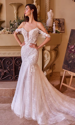 A woman stands indoors in the Andrea and Leo WL051 long wedding dress, an off-the-shoulder mermaid gown with lace applique and a long train, surrounded by classical decor and artwork.