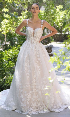 A woman stands in a garden wearing the Andrea and Leo WL058 long wedding dress in off white/nude, featuring a sleeveless floral lace bodice, delicate floral details, and an elegant a-line full skirt.