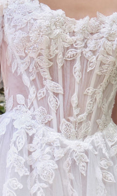 Close-up of the Andrea and Leo WL089 long wedding dress featuring off-the-shoulder design, floral lace appliques, beading, and sheer detailing on the bodice and upper skirt.