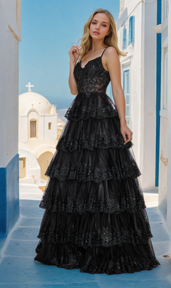 A woman stands on a white stone path before Mediterranean-style buildings, wearing the Sheer-Bodice Long Ruffle Prom Ball Gown: Poly 9402 with an embroidered lace bodice and delicate spaghetti straps.