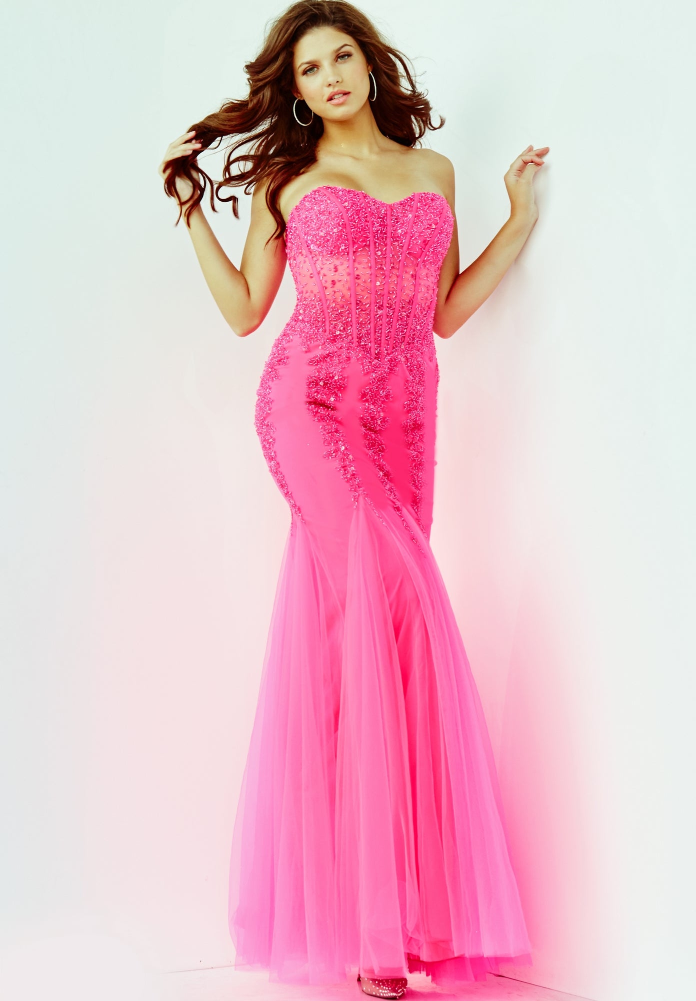 A woman poses against a plain white background wearing the Long Strapless Sweetheart Jovani Prom Dress 5908, a fitted bright pink gown featuring beadwork.