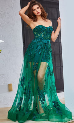 A woman poses indoors near a black door in the Jovani Strapless Sweetheart Sheer Corset Prom Dress, featuring floral appliqué details and a sheer green design.