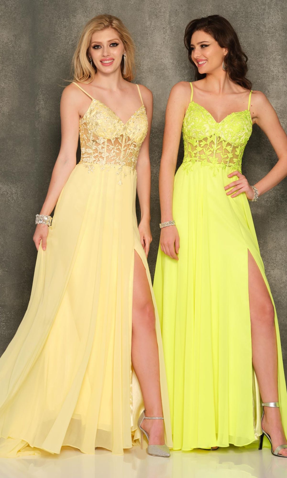 Two women pose against a gray textured background, wearing Sheer-Bodice Dave & Johnny Long Prom Dresses with lace bodices and thigh-high slits.