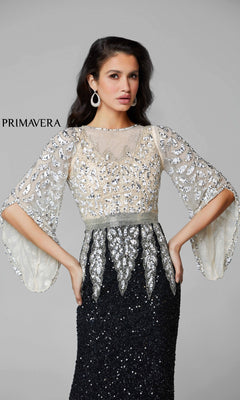 A woman poses with hands on hips in the Bell-Sleeve Long Beaded Evening Gown 1424, featuring black and silver beadwork, sheer embellished sleeves, and a sequin skirt. "PRIMAVERA" appears on the left against a plain background.