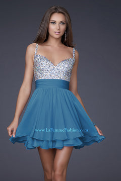 A woman models the La Femme Short Tiered Party Dress with sparkling silver beaded bodice, fitted waistband, and flowy sleeveless blue chiffon skirt against a plain gray background.