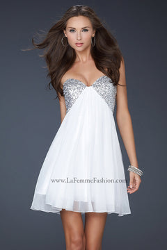 A woman in the La Femme 17649 Strapless Short Chiffon Hoco Dress with a sequin sweetheart bodice, hoop earrings, and bracelets stands against a plain dark background.