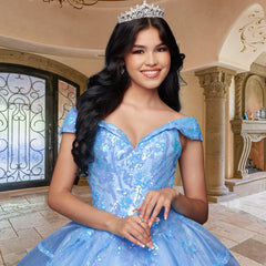 A woman wearing the Quinceañera Sample Dress QF104 and a tiara stands indoors, smiling with her hands clasped in front of her.