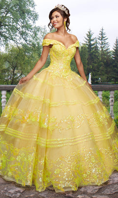 A young woman stands outdoors wearing the Quinceañera Sample Dress QF104, an off-the-shoulder gown with sequin details, complemented by a sparkling tiara.
