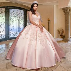 Young woman in the Quinceañera Sample Dress QF106—a light pink, v-neck gown with delicate embroidery and a tiara—standing in an elegant, tiled room with arched double doors and columns.