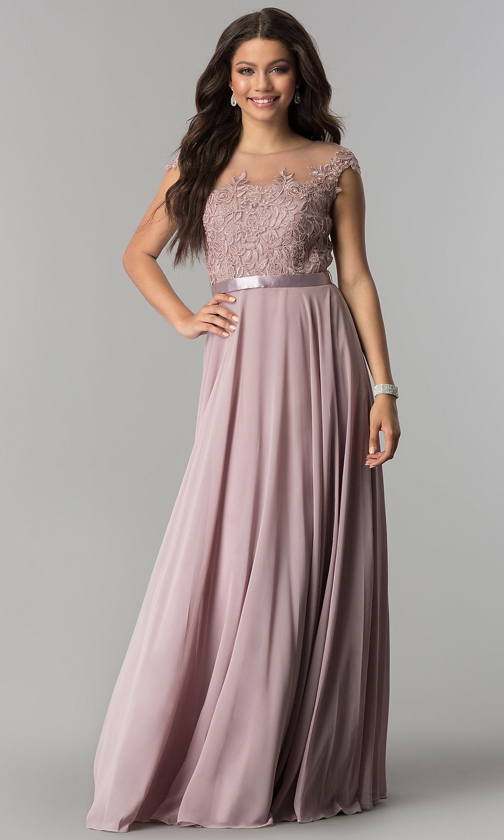 A woman stands against a neutral background wearing the Long Embroidered-Bodice Cap-Sleeve Chiffon Prom Dress, a floor-length mauve gown featuring an embroidered bodice, cap sleeves, and a satin waistband.
