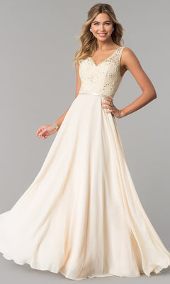 A woman in a V-Neck Sleeveless Lace-Bodice Long Prom Dress stands against a plain gray background, smiling and holding the skirt.