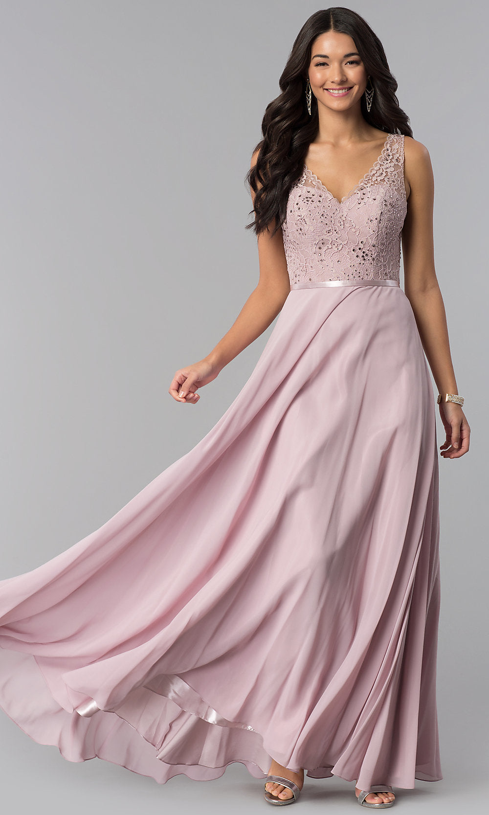 A woman wears the V-Neck Sleeveless Lace-Bodice Long Prom Dress with a flowing chiffon skirt, standing against a plain gray background.