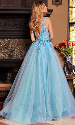 A woman with long blonde hair stands indoors by a fireplace wearing the Jovani Tulle Prom Ball Gown with Floral Embroidery, featuring a deep V-back and a flowing floor-length tulle skirt.