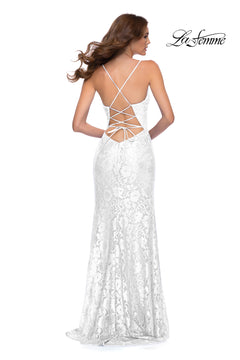 A woman stands with her back to the camera, wearing the Open-Back La Femme Long Lace Prom Dress 29939 featuring a crisscross open back, fitted silhouette, and elegant white lace.