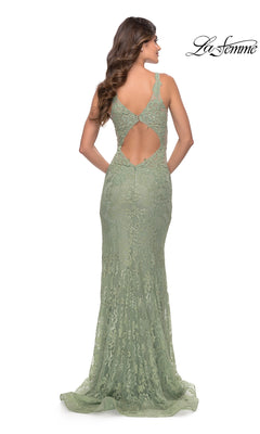 A woman stands facing away, wearing the La Femme Long Lace Prom Dress with Plunging V-Neck in light green, featuring floral lace and a keyhole back. The La Femme logo appears in the top right corner.