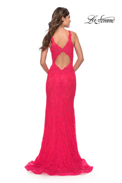 A woman stands facing away in a bright pink La Femme 29978 deep V-neck long lace prom dress with a cutout back. The La Femme logo is in the top right corner.