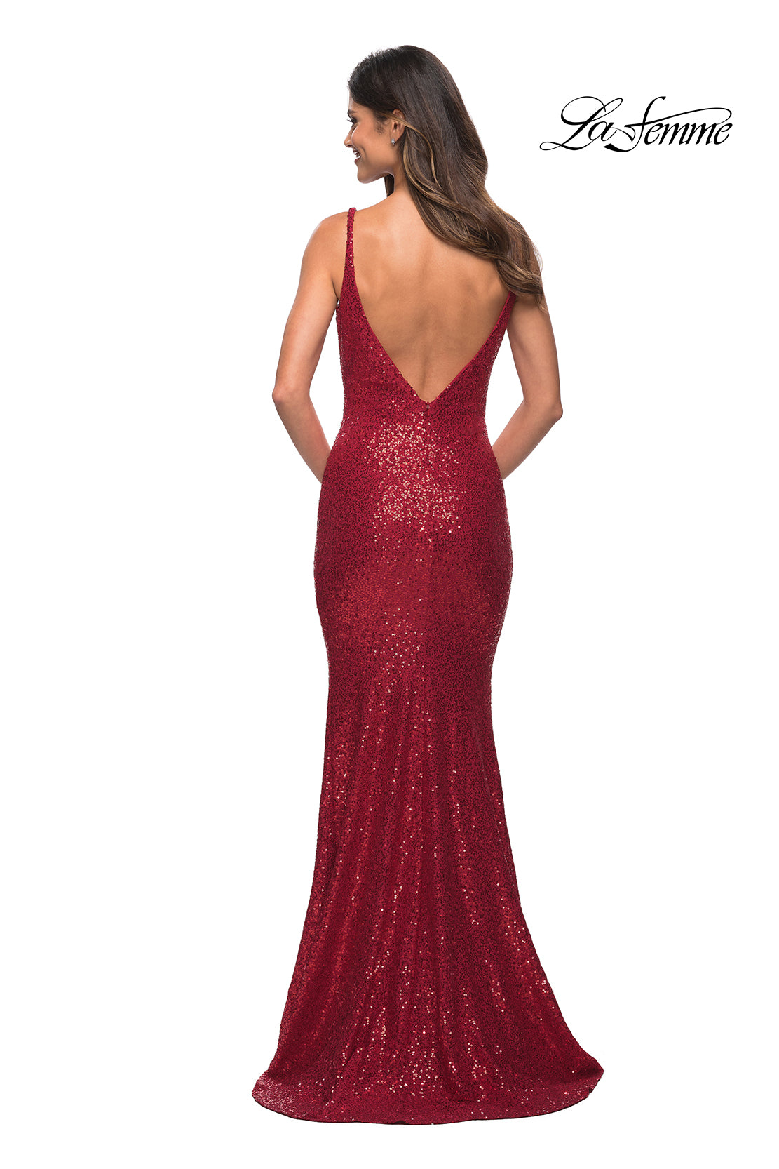 A woman stands facing away in the La Femme Floor-Length V-Neck Sequin Prom Dress, a fitted red gown with sleeveless design and deep V-back; 