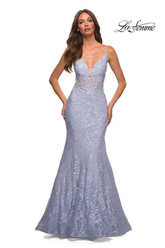A woman models the La Femme Lace Sheer-Waist Long Mermaid Prom Dress in light lavender, featuring a deep V neckline, thin straps, and sheer corset details, standing before a plain white background with the La Femme logo top right.