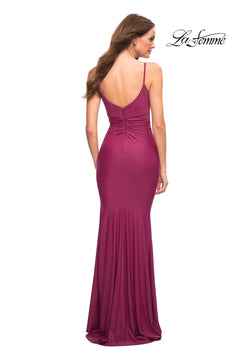 A woman is standing with her back to the camera, wearing the Cowl-Neck Long Jersey Prom Dress by La Femme—a floor-length, fitted magenta gown with thin straps and a low back.