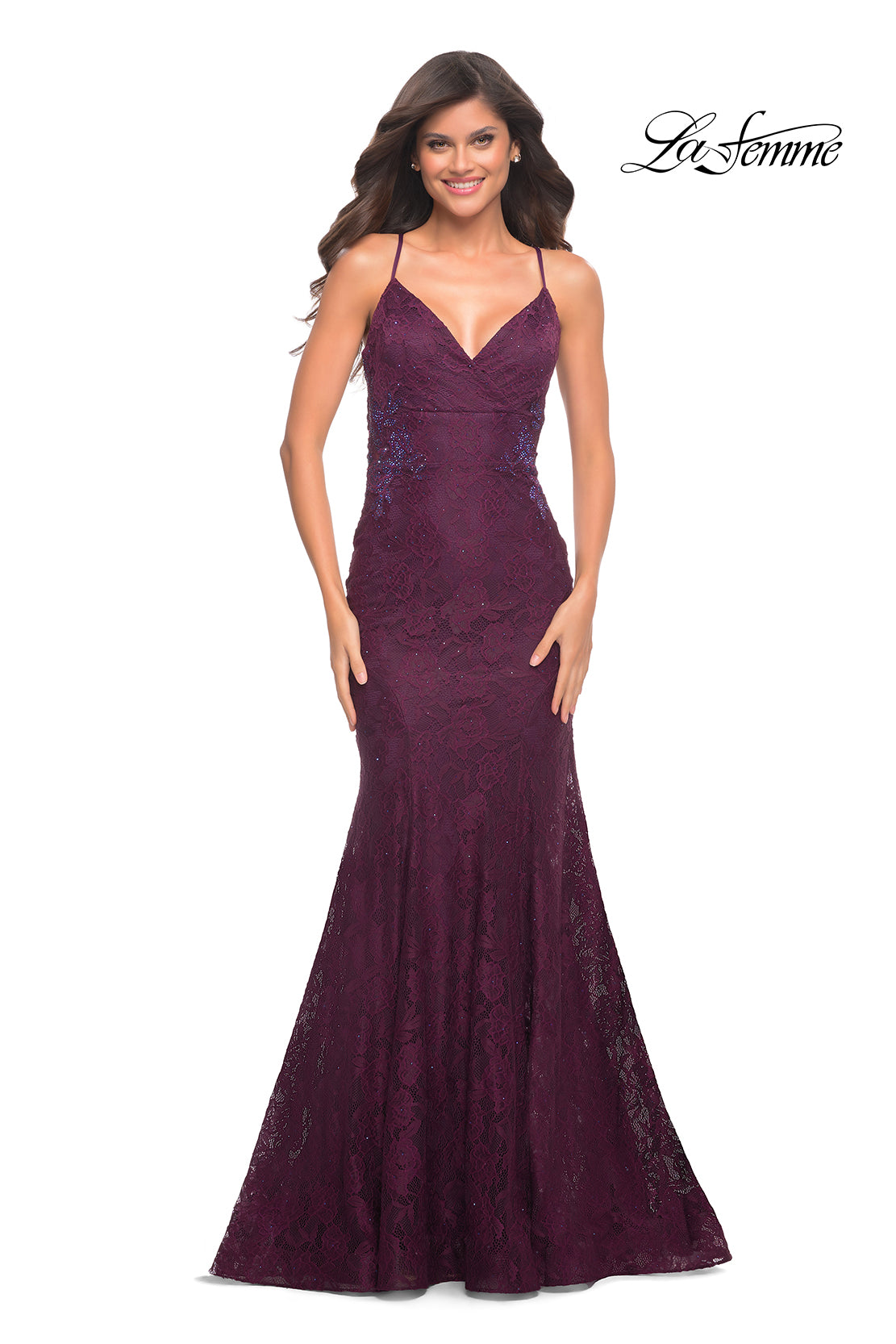 A woman models the La Femme Long Lace Formal Dress with a corset back, featuring thin straps, a fitted bodice, and a flared floor-length dark purple skirt. The 