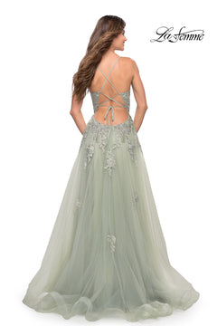 A woman wears a light green La Femme Open-Back Long Ball Gown with lace, featuring floral embroidery, a crisscross open back, and a full tulle skirt. The La Femme brand appears in the top right corner.