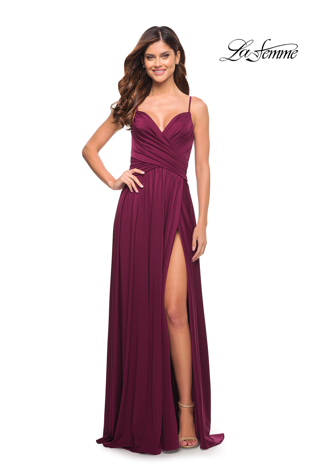 A woman stands smiling in a sleeveless, floor-length burgundy La Femme Simple Elegant Long Formal Prom Dress with a thigh-high slit. The La Femme logo is displayed in the top right corner.