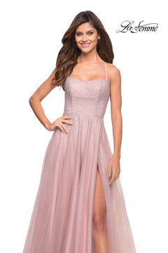 A woman wears the Corset-Back Long La Femme A-Line Prom Dress—a sleeveless, light pink beaded formal gown with a thigh-high slit—standing and smiling against a white background. The La Femme logo appears in the top right corner.