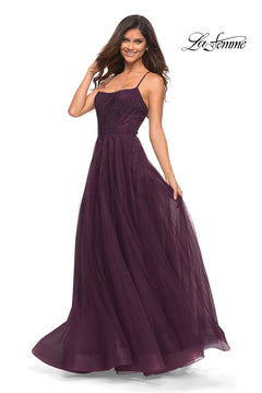 A woman poses against a white background in the Corset-Back Long La Femme A-Line Prom Dress, a sleeveless, floor-length dark purple gown featuring thin straps and a tulle skirt. The "La Femme" logo appears in the upper right corner.