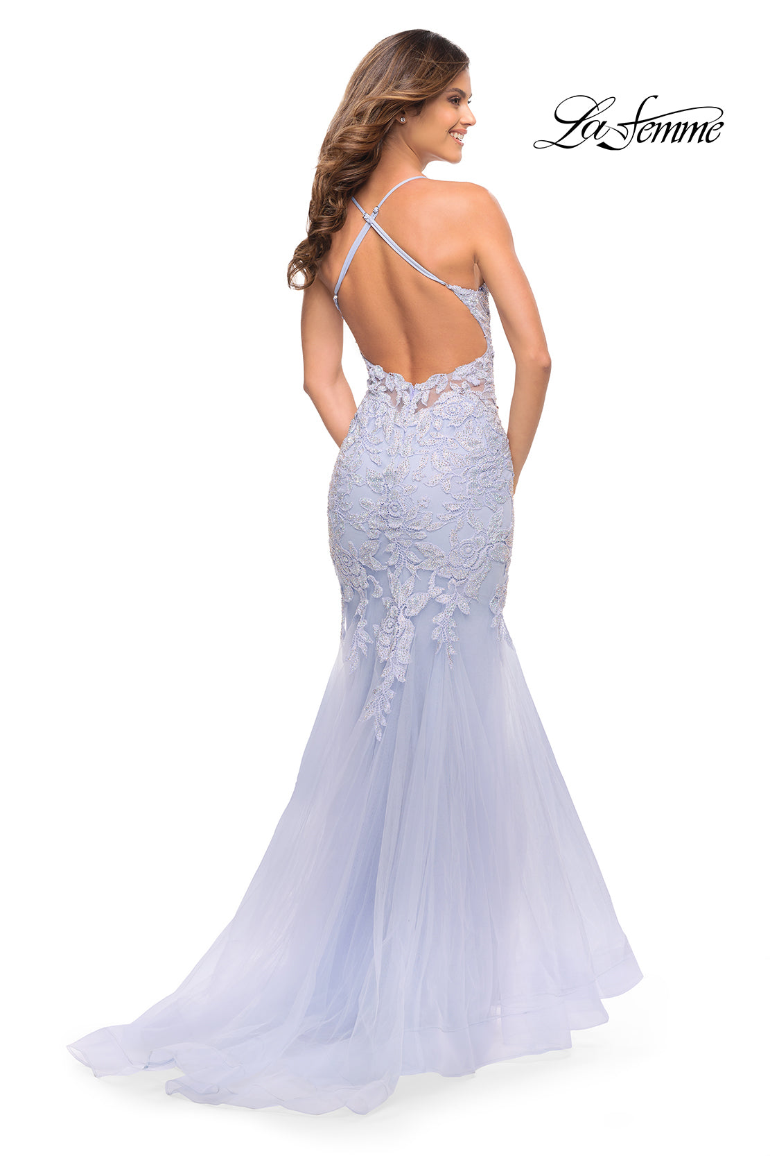Woman in a light blue Backless Long Lace Mermaid Prom Dress by La Femme with tulle and a crisscross open back, standing and facing away; the La Femme logo appears in the top right corner.
