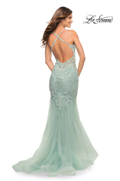 A woman models the Backless Long Lace Mermaid Prom Dress by La Femme in light blue, featuring an open back with crisscross straps, as she poses facing away from the camera. The "La Femme" logo appears in the top right corner.