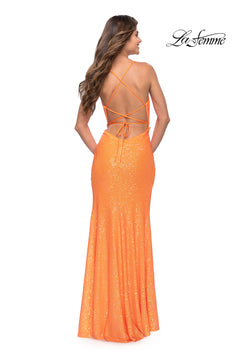 A woman in the La Femme Faux-Wrap Long Sequin Formal Gown, a floor-length orange dress with a strappy open back, stands facing away from the camera. The La Femme logo is displayed in the upper right corner.