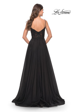 A woman models the La Femme Long A-Line Prom Dress with a sheer lace bodice, thin straps, and a flowing black skirt, shown from the back. The La Femme logo is in the top right corner.