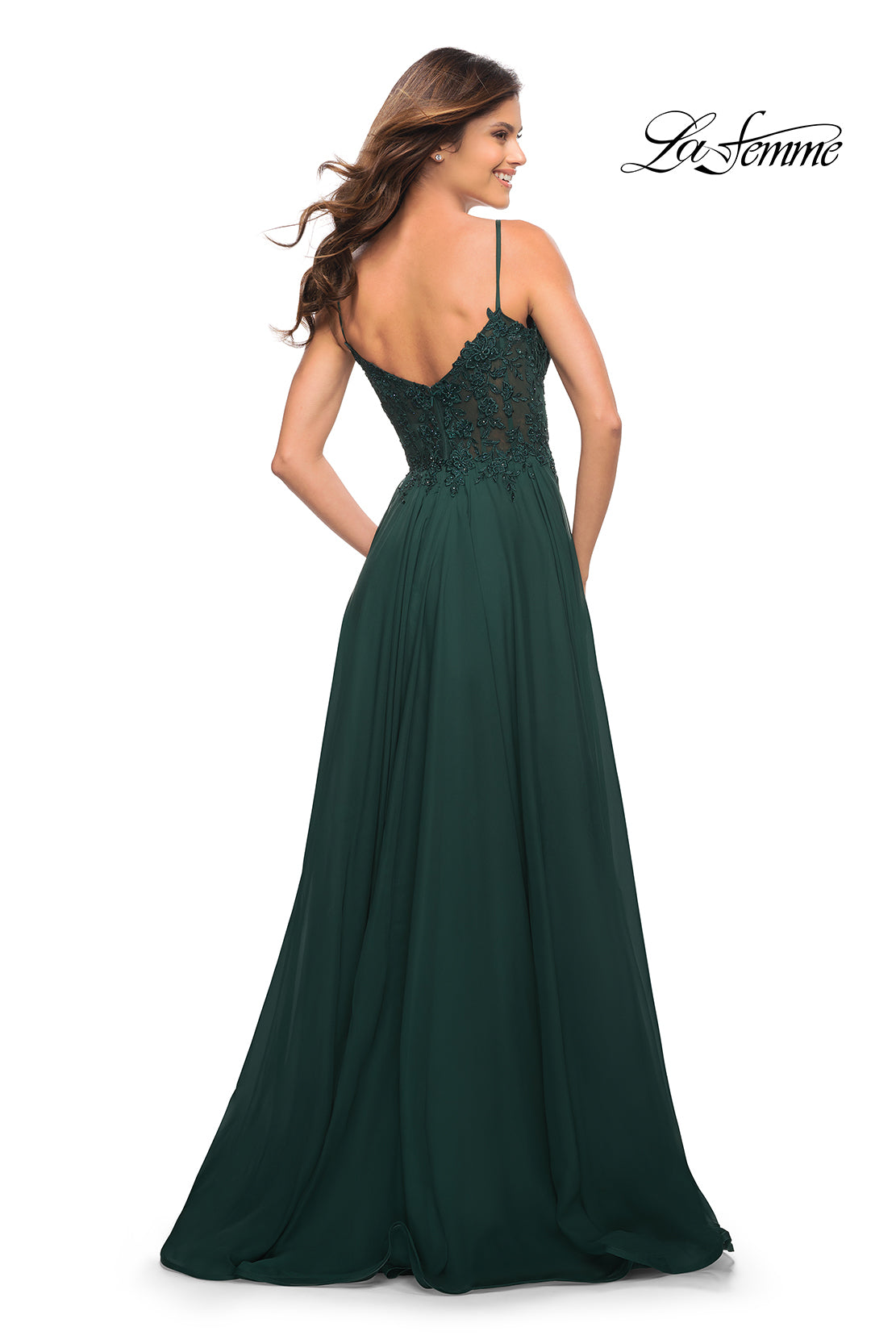 Woman in a dark green La Femme Long A-Line Prom Dress with a sheer bodice and thin straps, facing away; 