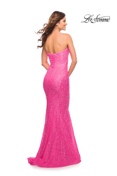 A woman faces away in a sparkling, strapless, floor-length neon pink sequin prom gown. The "La Femme" logo is displayed in the top right corner. Product: La Femme Neon Pink Strapless Long Sequin Prom Gown.